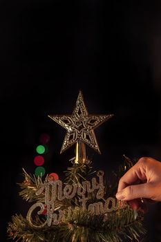 Christmas background concept- beautiful decor bauble hanging on the Christmas tree with sparkling light spot, blurry dark black background, copy space, close up.