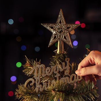 Christmas background concept- beautiful decor bauble hanging on the Christmas tree with sparkling light spot, blurry dark black background, copy space, close up.