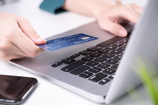 Office online paying, stay home shopping, electronic payment with credit card concept, laptop on white table background with shop cart, close up.
