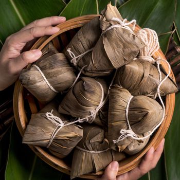 Rice dumpling, zongzi - Traditional Chinese food on green leaf background of Dragon Boat Festival, Duanwu Festival, top view, flat lay design concept.