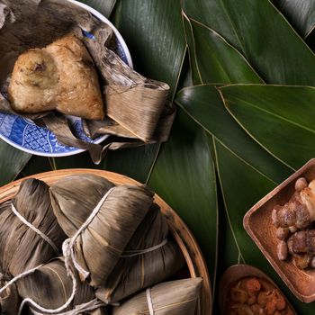 Rice dumpling, zongzi - Traditional Chinese food on green leaf background of Dragon Boat Festival, Duanwu Festival, top view, flat lay design concept.