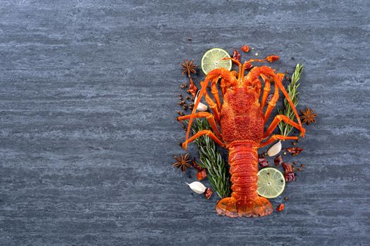 Cooked boiled lobster, delicious dinner seafood meal set with knife and fork on black stone slate background, restaurant menu design, top view, overhead
