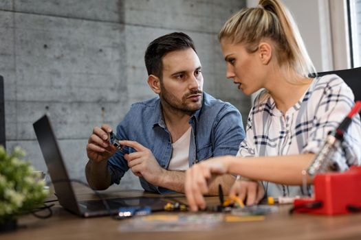 Two young business partners technician focused on the repair of electronic equipment.