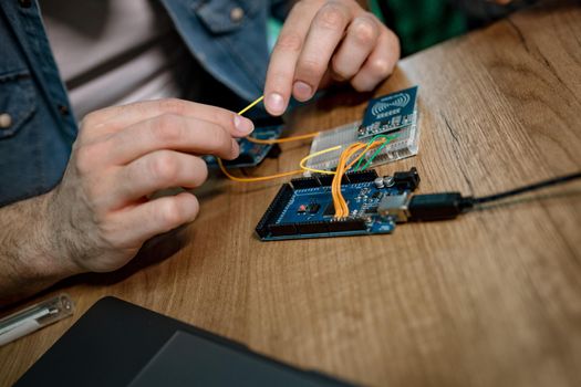 Close-up of a male hands soldering circuit board on the table.