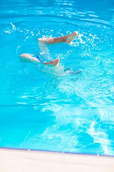 Cute happy little boy in goggles swimming and snorking in the swimming pool. Swimming for kids concept