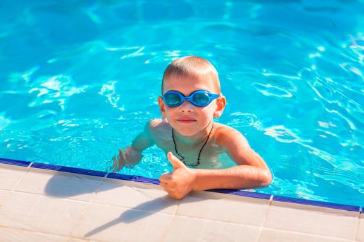 Cute happy little boy in goggles swimming and snorking in the swimming pool. Swimming for kids concept