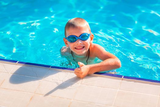 Cute happy little boy in goggles swimming and snorking in the swimming pool. Swimming for kids concept