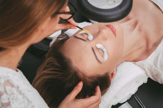 Beautician preparing model for applying extended eyelashes. 