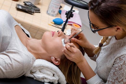 Beautician applying extended eyelashes to model at the beauty salon.