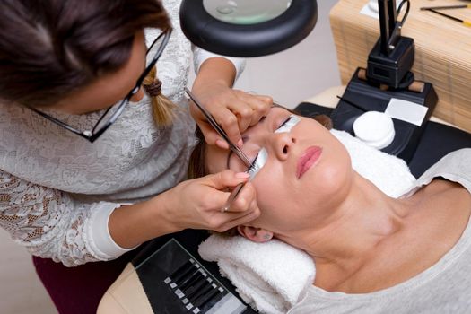 Beautician applying extended eyelashes to model at the beauty salon.