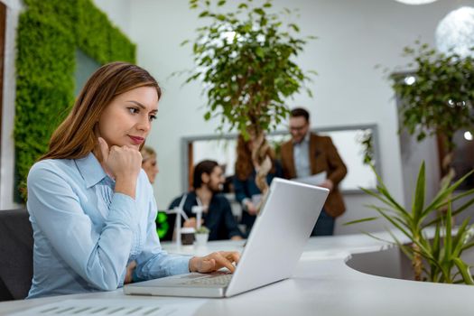 Young beautiful serious pensive worried businesswoman analyzing bussiness plans and working on laptop in the office.