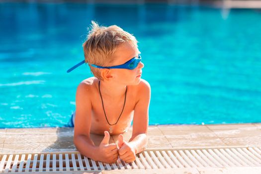 Cute happy little boy in goggles swimming and snorking in the swimming pool. Swimming for kids concept