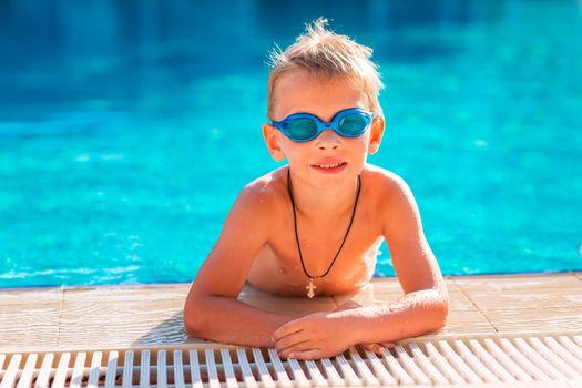 Cute happy little boy in goggles swimming and snorking in the swimming pool. Swimming for kids concept