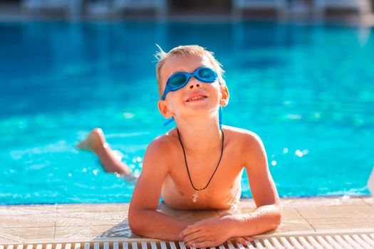 Cute happy little boy in goggles swimming and snorking in the swimming pool. Swimming for kids concept