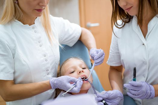 Pediatric dentist checking teeth of theyoung girl  patient at the dental office. 