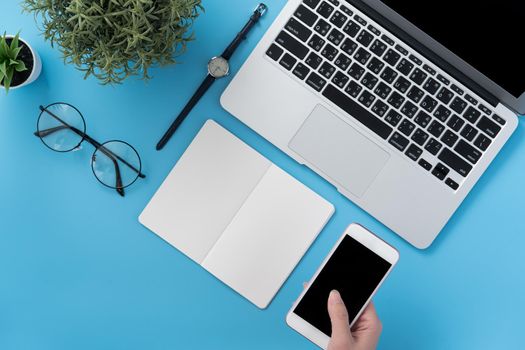 Concept of home office table with fashion accessories, minimal interior with a woman holding smartphone, flat lay, copy space, top view, mockup