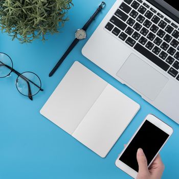 Concept of home office table with fashion accessories, minimal interior with a woman holding smartphone, flat lay, copy space, top view, mockup
