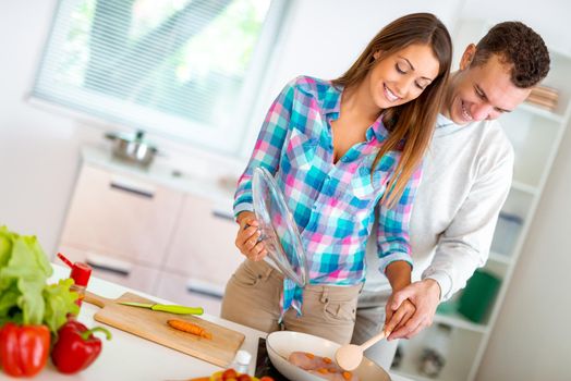 Beautiful young couple cooking healthy meal in the domestic kitchen. 