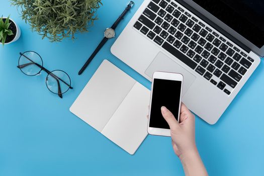 Concept of home office table with fashion accessories, minimal interior with a woman holding smartphone, flat lay, copy space, top view, mockup