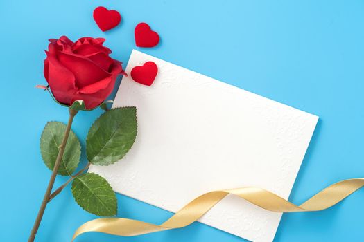 Beautiful greeting card with golden ribbon for Valentine's day, anniversary, mother's day and birthday on blue background, copyspace, topview, mockup, flatlay
