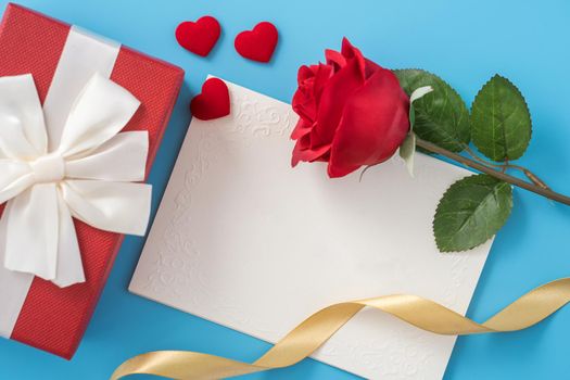 Beautiful greeting card with golden ribbon for Valentine's day, anniversary, mother's day and birthday on blue background, copyspace, topview, mockup, flatlay