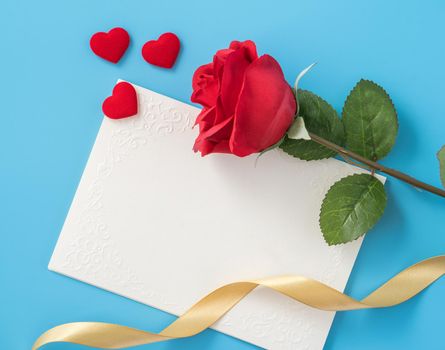 Beautiful greeting card with golden ribbon for Valentine's day, anniversary, mother's day and birthday on blue background, copyspace, topview, mockup, flatlay