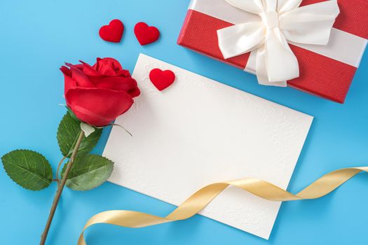 Beautiful greeting card with golden ribbon for Valentine's day, anniversary, mother's day and birthday on blue background, copyspace, topview, mockup, flatlay