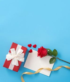 Beautiful greeting card with golden ribbon for Valentine's day, anniversary, mother's day and birthday on blue background, copyspace, topview, mockup, flatlay