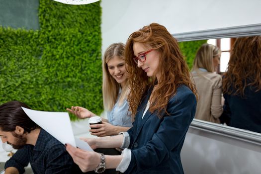 Two business women in a serious discussion standing in the office together looking at paperwork.