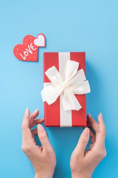 A young woman is giving a gift with greeting on blue background, concept of holiday and celebrate for festival surprising, copyspace, topview