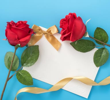 Beautiful greeting card with golden ribbon for Valentine's day, anniversary, mother's day and birthday on blue background, copyspace, topview, mockup, flatlay