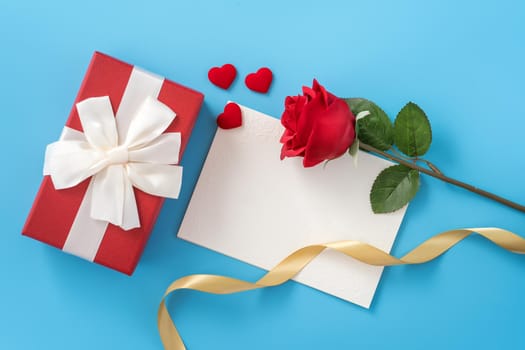 Beautiful greeting card with golden ribbon for Valentine's day, anniversary, mother's day and birthday on blue background, copyspace, topview, mockup, flatlay