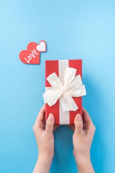 A young woman is giving a gift with greeting on blue background, concept of holiday and celebrate for festival surprising, copyspace, topview