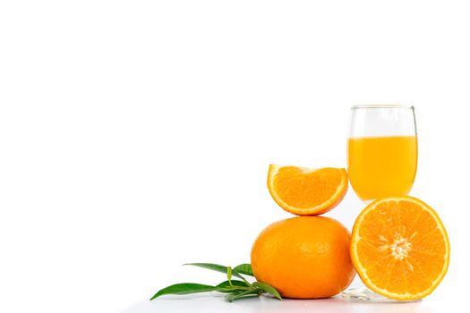 Freshly squeezed orange juice in a glass decorated with citrus fruits and orange leaves on white background with copy space