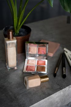 Makeup products for skin tone. Foundation, eye shadow palette in rose gold and nude colors closeup. Cosmetics for professional makeup artist