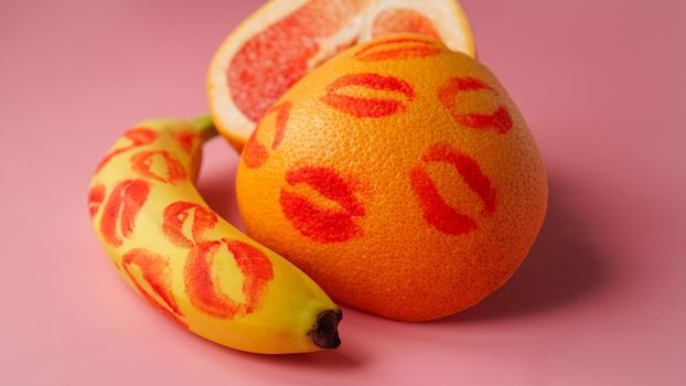 Composition with fresh banana and grapefruit with traces of red lipstick on pink background. Love concept