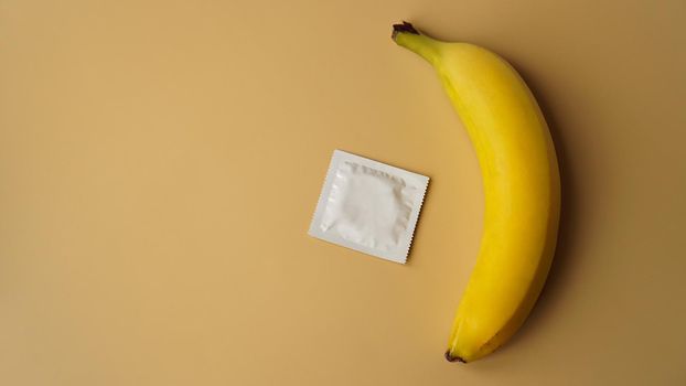 Condoms and banana on golden background, the concept of contraceptives and the prevention of venereal diseases