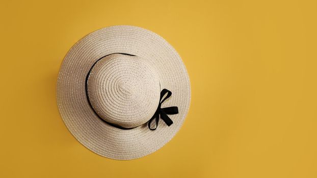 Summer straw hat on yellow background top view flat lay copy space. Summer travel vacation concept, single item. Female accessory, summer background