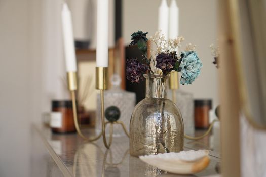Home interior decor. Glass jar with dried flowers, vase and candle. Living room decoration.
