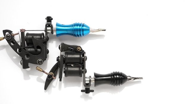 Two tattoo machines on a white background - tattoo industry -space for text