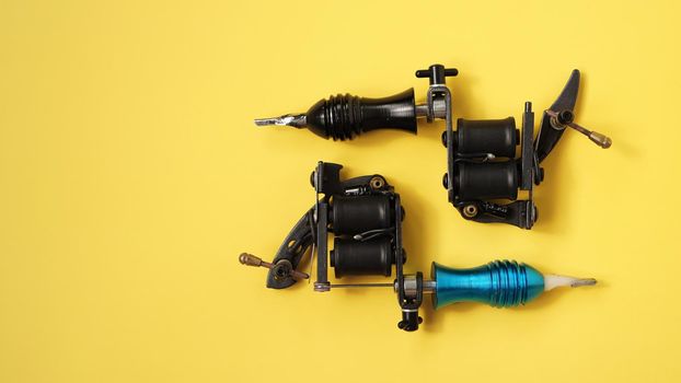 Two tattoo machines on a yellow background - tattoo industry