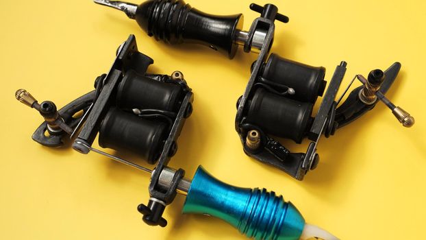 Two tattoo machines on a yellow background - tattoo industry