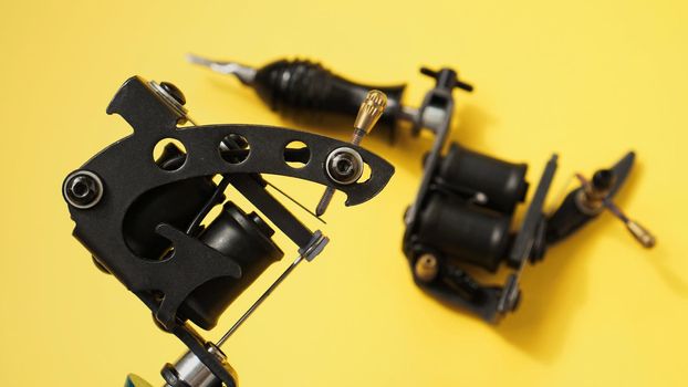 Two tattoo machines on a yellow background - tattoo industry