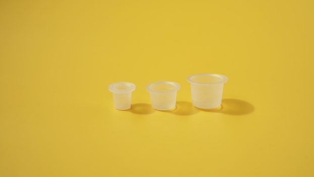 Three ink plastic caps on yellow background - tattoo concept