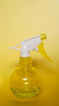Spray bottle on yellow background. Portable pressure water sprayer pump. Sprayer bottle - vertical photo