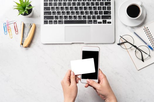 A woman is doing a online purchase, mock up credit card and mobile cellphone on office desk isolated on beautiful fashion marble background, copy space, topview, flatlay, closeup