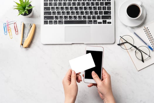 A woman is doing a online purchase, mock up credit card and mobile cellphone on office desk isolated on beautiful fashion marble background, copy space, topview, flatlay, closeup