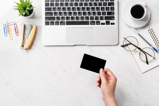 A woman is doing a online purchase, mock up credit card and mobile cellphone on office desk isolated on beautiful fashion marble background, copy space, topview, flatlay, closeup