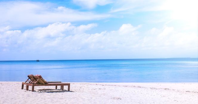 Chairs on the amazing beautiful sandy beach near the ocean with blue sky. Concept of summer leisure calm vacation for a tourism idea. Empty copy space, inspiration of tropical landscape