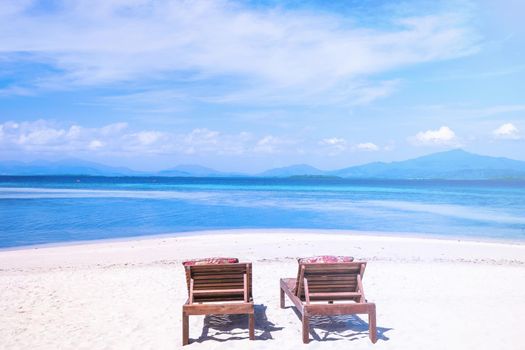 Chairs on the amazing beautiful sandy beach near the ocean with blue sky. Concept of summer leisure calm vacation for a tourism idea. Empty copy space, inspiration of tropical landscape